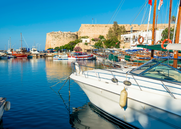 Kyrenia Hafen in Nordzypern mit bunten Booten vor einer Festung und klarem blauem Wasser.