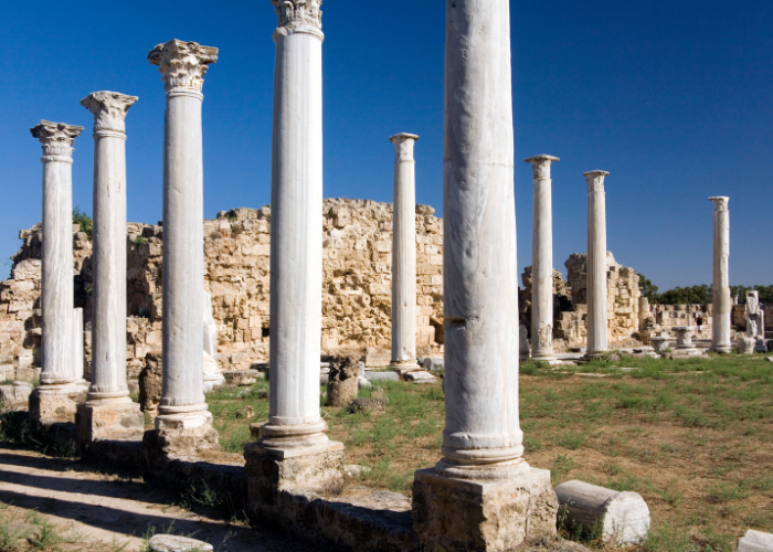 Die antiken Ruinen von Salamis in Nordzypern mit einer Reihe von mächtigen, gut erhaltenen Säulen unter klarem blauem Himmel.