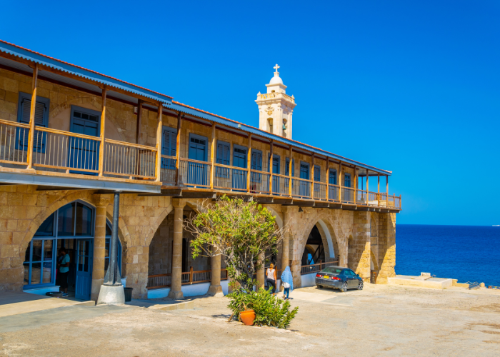 Ansicht der Apostolos Andreas Monastery in Nordzypern, ein großes Steingebäude mit Arkaden, überblickt das azurblaue Meer.